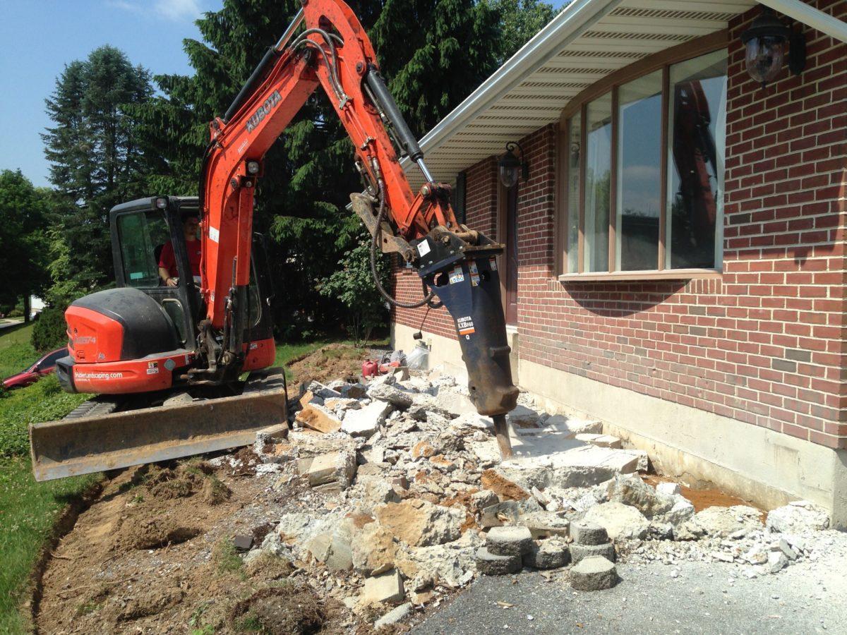Concrete removal process showing broken slabs ready for disposal and site preparation.