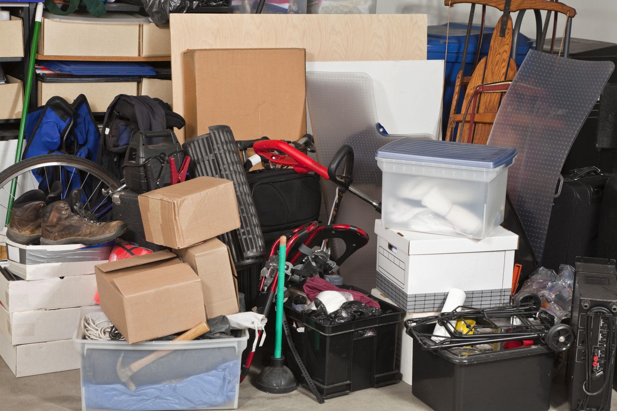 Cluttered residential garage filled with boxes, tools, and household items waiting to be organized